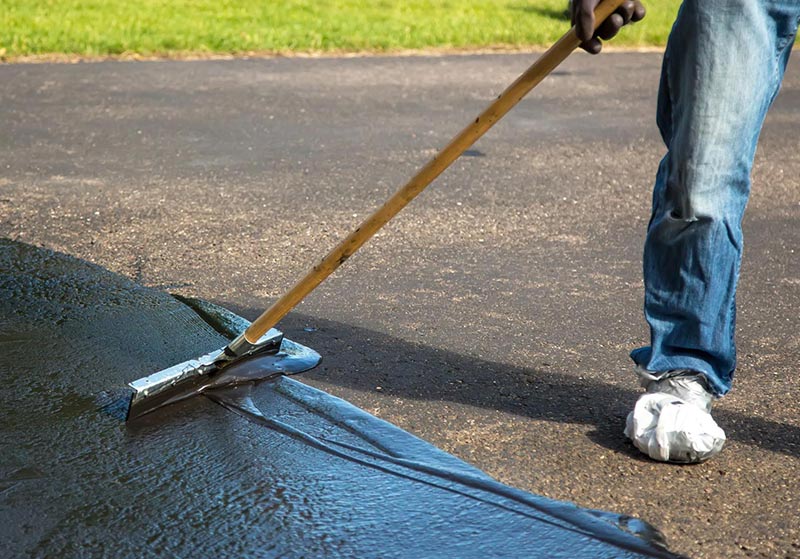 Contractor filling cracks in asphalt pavement